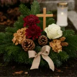 Grabgesteck zu Allerheiligen mit Tannengrün, Chrysanthemen und Holzkreuz auf Friedhof