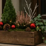 Weihnachtlich dekorierter Blumenkasten mit Fichte, Heide, Lichterkette und roten Kugeln