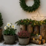 Winterdeko für die Hauswand mit Pflanzen, Lichterkette, Kranz und Laterne im Schnee