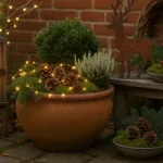 Winterdeko im kleinen Garten mit Laterne, Lichterkette, Töpfen und Zapfen