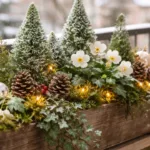 Winterlich dekorierter Blumenkasten mit Tannenzweigen, Moos, Zapfen und Lichterkette