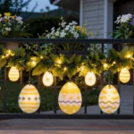 Osterbeleuchtung im Garten mit leuchtenden Ostereiern und Hasen am Geländer vor dem Hauseingang