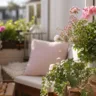 Balkondeko im Mai mit Blumen, Kissen und natürlicher Deko auf sonnigem Balkon