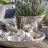 Gartendeko mit Muscheln auf Holztisch mit Windlichtern und Lavendel im Garten