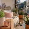 Sommer Deko für den Balkon mit modernen Pflanzkübeln, Holzmöbeln und stimmungsvoller Beleuchtung im Freien.