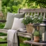 Gartenbank Deko im Mai mit Kissen, Pflanzen und Laterne im natürlichen Gartenstil