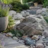 Gartendeko mit Steinen im modernen Garten mit Natursteinen, Kies und Lavendel im Sonnenlicht