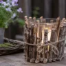 Gartendeko aus Ästen mit Windlicht auf Holztisch im natürlich dekorierten Garten.