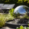 Gartendeko aus Edelstahl mit Kugelbrunnen zwischen Gräsern und modernem Gartenbereich