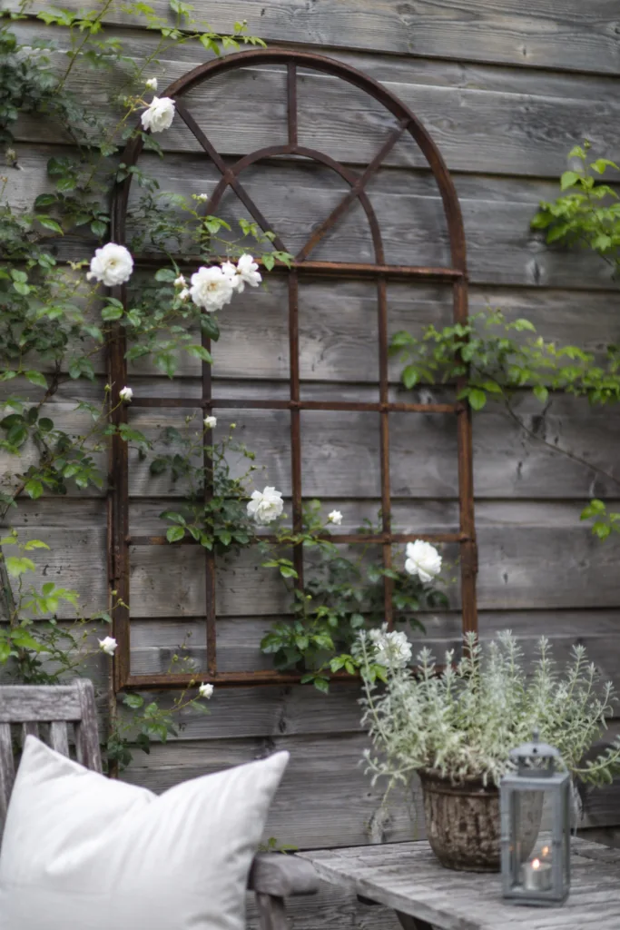 Gartendeko aus Eisen – 5 Ideen für mehr Struktur und Atmosphäre Gartendeko aus Eisen mit altem Metallfenster an Holzsichtschutz im Garten
