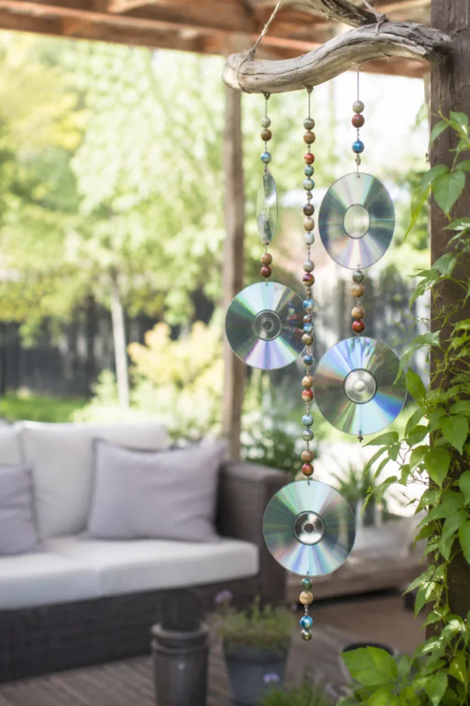 Gartendeko mit alten CDs – 5 kreative Ideen für mehr Licht im Garten Windspiel aus alten CDs auf Terrasse mit Lichtreflexen im Garten dekoriert.