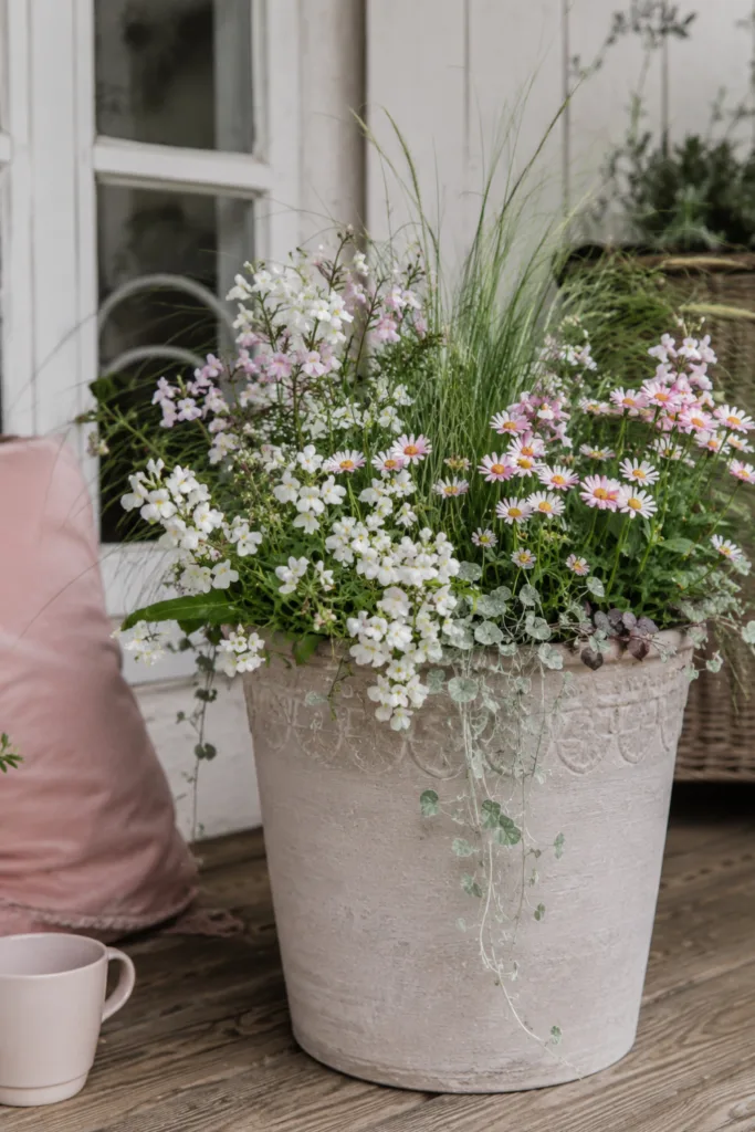 Pflanzkübel Deko im Mai mit romantischen Frühlingsblumen und sanften Farben auf Terrasse.