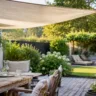 Sommerdeko für den Garten mit Sonnensegel als schattenspendender Sitzplatz auf einer Terrasse.