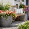 Vorgartendeko im Juni mit großem Pflanzkübel, Sommerblumen und einladendem Hauseingang.