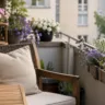 Deko für einen kleinen Balkon im Juni mit Sommerblumen, Holzmöbeln und natürlicher Balkongestaltung.