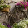 Gartendeko mit altem Fahrrad und Blumen als dekorativer Blickfang im naturnahen Garten vor Holzwand.