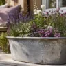 Gartendeko mit alter Zinkwanne als bepflanzter Blumenkübel auf Terrasse im naturnahen Garten.