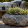 Terrassendeko mit Steinen auf Holzterrasse mit bepflanztem Naturstein und gemütlichem Sitzbereich im Garten.