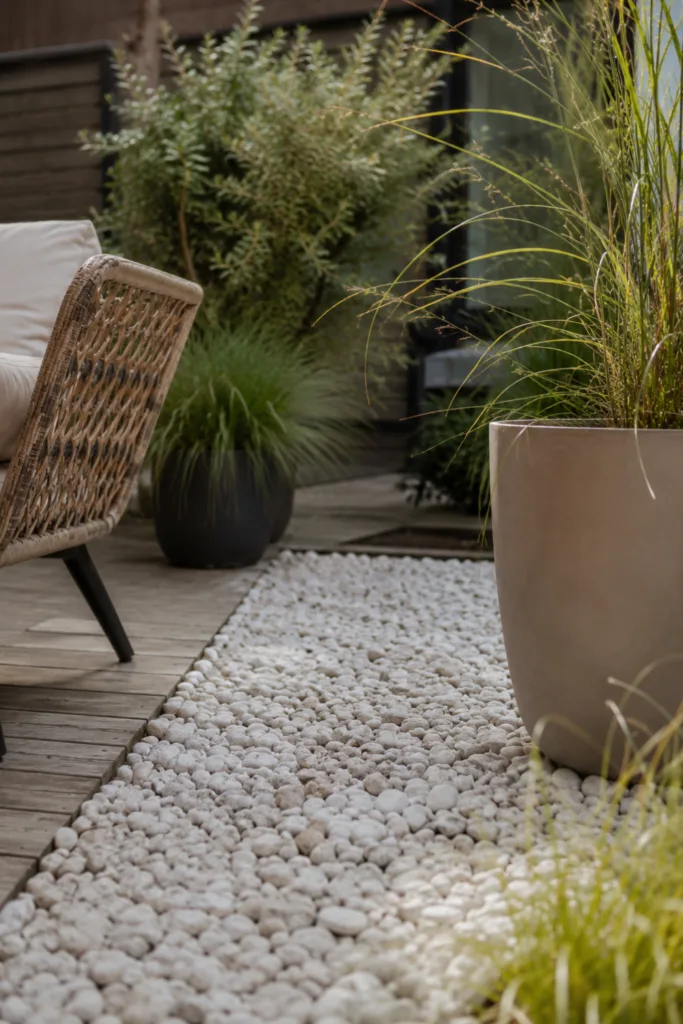 Terrassendeko mit Steinen: Helle Kiesfläche zwischen Pflanzkübeln und Holzterrasse als ruhiges Gestaltungselement.