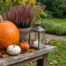 Herbstdeko für den Garten mit Kürbissen, Heide, Laterne und Hagebutten auf einer rustikalen Holzbank.