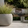 Terrassendeko mit Beton: großer Pflanzkübel mit Ziergras auf einer modern gestalteten Terrasse.