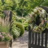 Gartentordeko im Juli mit Blumenkranz, Pflanzkübel und rustikalem Holztor.