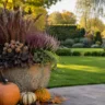 Herbstdeko für einen großen Garten mit großem Pflanzkübel, Kürbissen und Laterne auf der Terrasse.