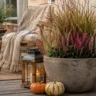 Herbstdeko für eine kleine Terrasse mit Pflanzkübel, Laterne, Kürbissen und gemütlichem Sitzplatz.