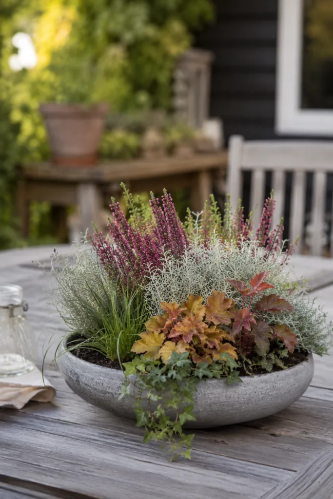 Herbstdeko für den Gartentisch mit bepflanzter Schale, Heide, Silberblatt und herbstlichem Laub.