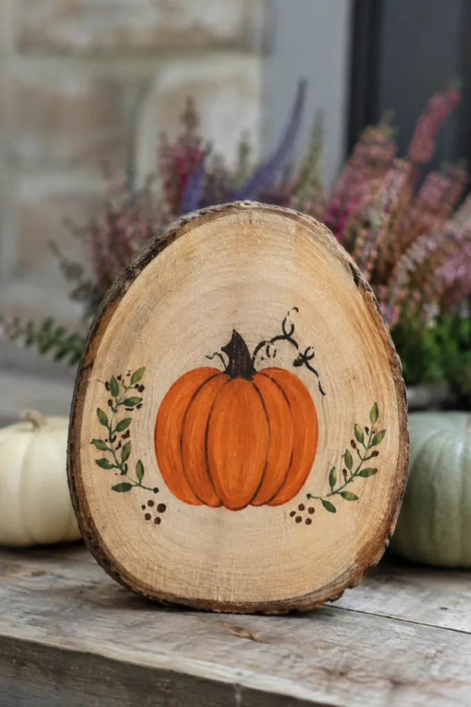 Herbstdeko basteln für den Garten: 5 Ideen aus natürlichen Materialien Bemalte Holzscheibe mit Kürbismotiv als selbst gebastelte Herbstdeko für den Garten.