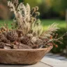 Herbstdeko mit Naturmaterialien im Garten: rustikale Schale mit Zapfen, Zweigen, Gräsern und Hagebutten.