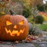 Leuchtender Kürbis mit Laterne als gruselige Halloweendeko im Garten auf herbstlichem Gartenweg.