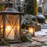 Weihnachtsdeko mit Laternen am verschneiten Gartenweg mit Tannengrün und warmem Kerzenlicht.