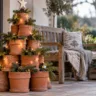 Weihnachtsbaum aus gestapelten Tontöpfen mit Tannenzweigen, Lichterkette und Holzstern auf einer Terrasse.