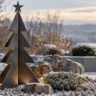 Moderne Weihnachtsdeko für den Steingarten mit schwarzem Metallstern, Naturstein und beleuchteter Laterne.