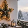 Wetterfeste Weihnachtsdeko auf dem Balkon mit großem Weihnachtsstern, Lichterkette und verschneitem Geländer.