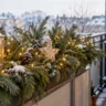 Weihnachtsdeko für den Balkon mit Tannengrün, Lichterkette, Laterne und winterlicher Dekoration.