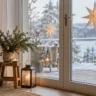 Weihnachtsdeko für die Terrassentür mit Tannengirlande, wintergrünen Pflanzen und warmen Lichtern.